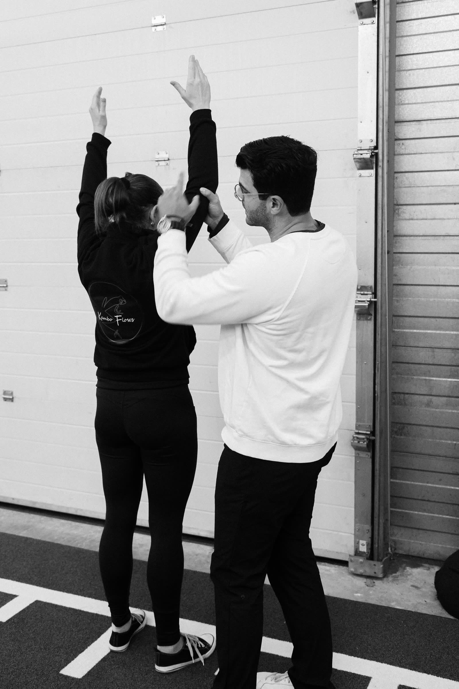 Richard Aceves coaching a participant through an arms-overhead position during an in-person Moved Academy seminar.