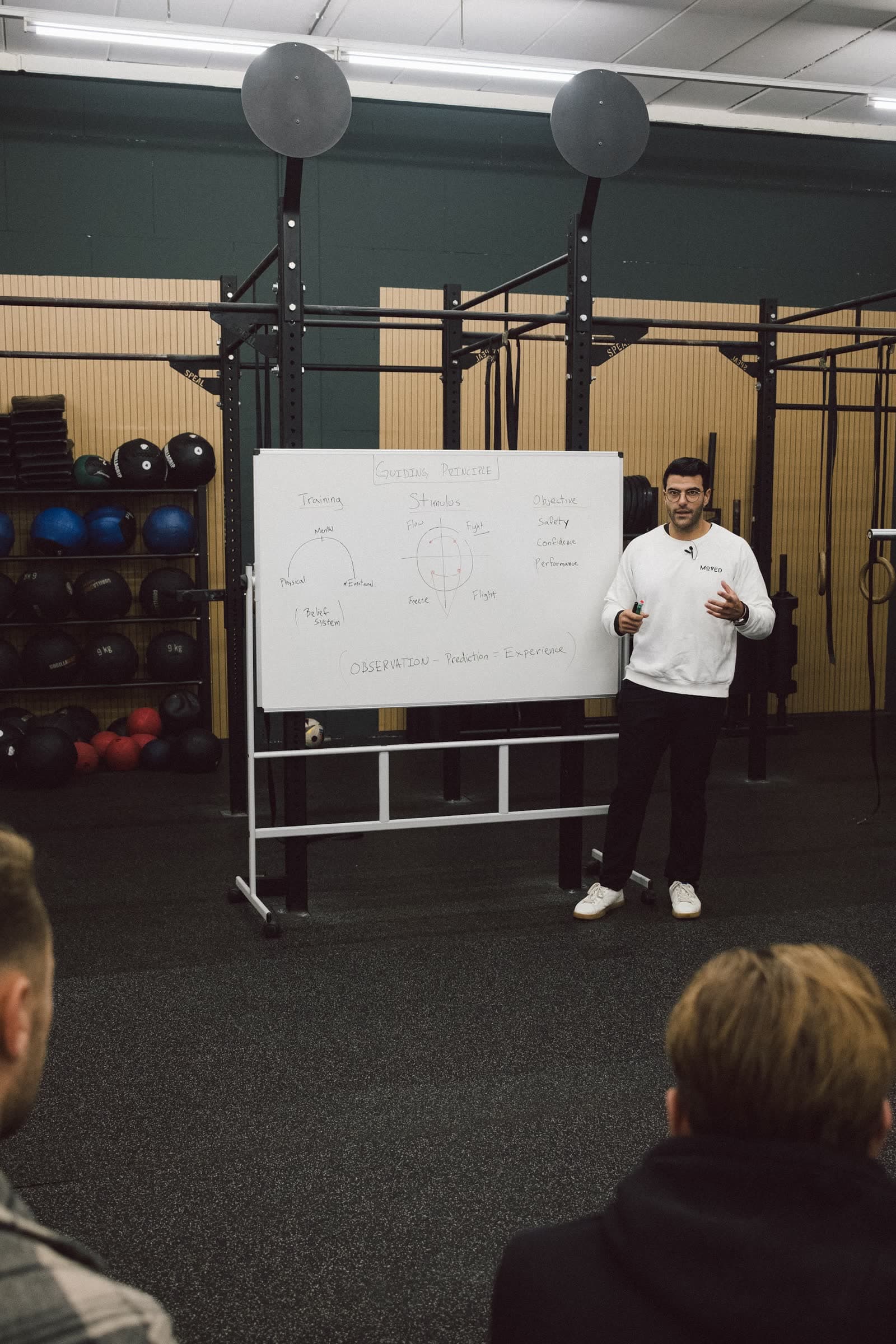 Richard Aceves teaching at a whiteboard while coaches listen, during an in-person Moved Academy seminar.